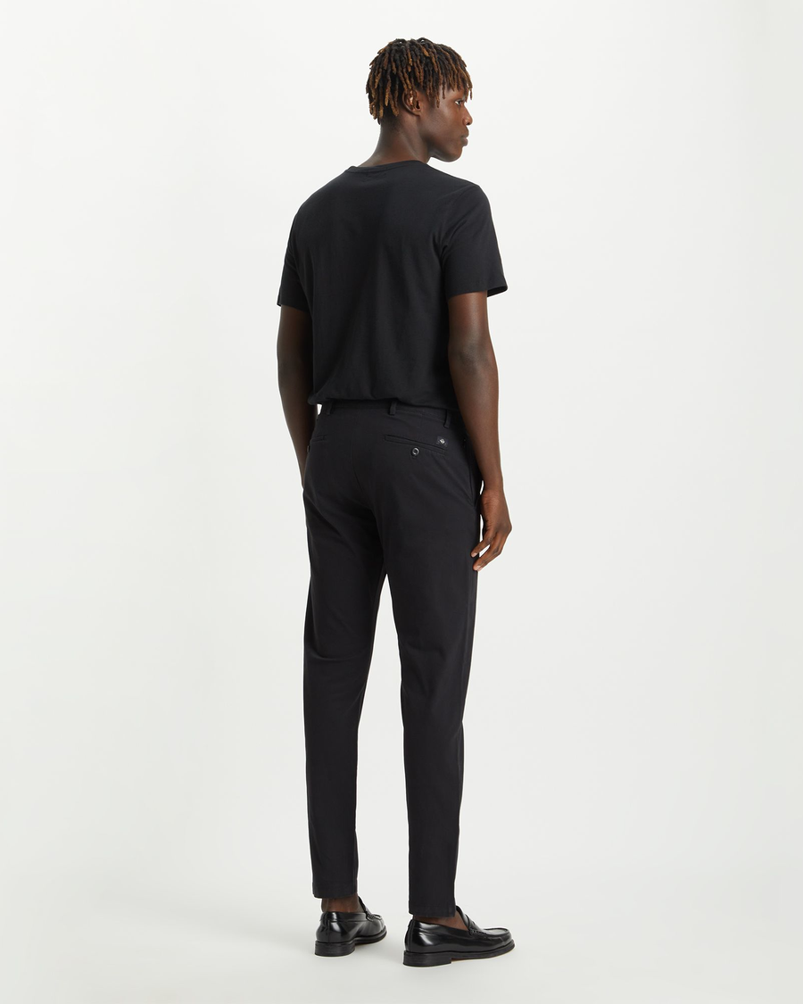 Back view of model wearing Black Men's Slim Tapered Fit Smart 360 Flex Alpha Chino Pants.