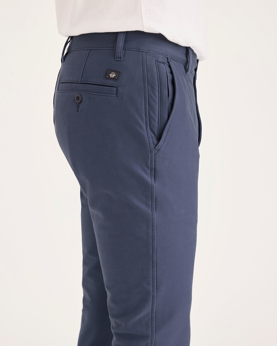 Side view of model wearing Crown Blue Men's Skinny Fit Smart 360 Knit Chino Pants.