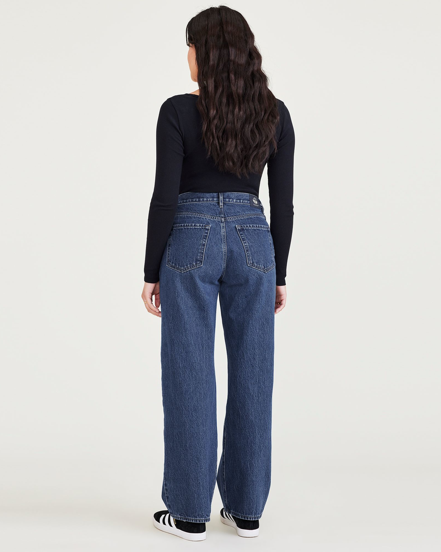 Back view of model wearing Medium Indigo Stonewash Women's Relaxed Fit Mid-Rise Jeans.