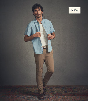 Man wearing a light blue shirt over a white t-shirt and beige NEW Ultimate Chino pants on a gray background.