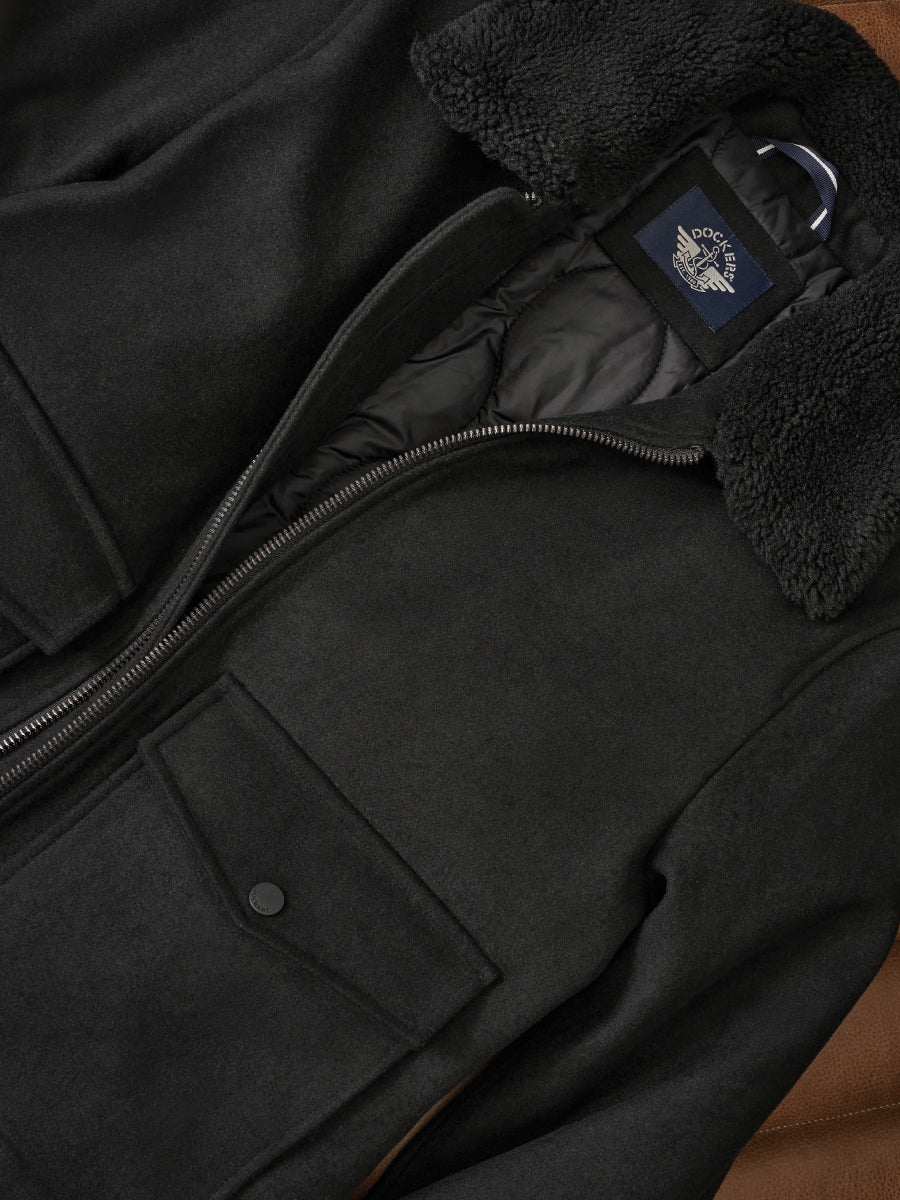 Close-up of a black coat with a brand logo on a brown surface